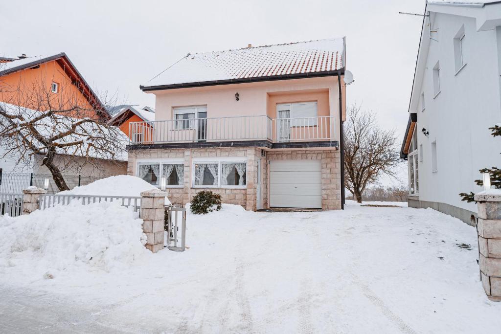 a white house with a garage in the snow at CosyHouse-Kupres in Kupres