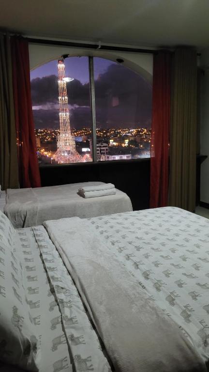 two beds in a bedroom with a view of the eiffel tower at Apartamento 906 zona 9 in Guatemala