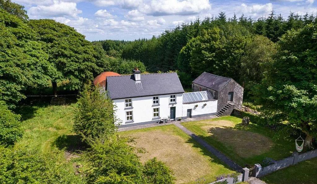 an aerial view of a white house in the woods at Cosy Cottage in Galway in Creggs