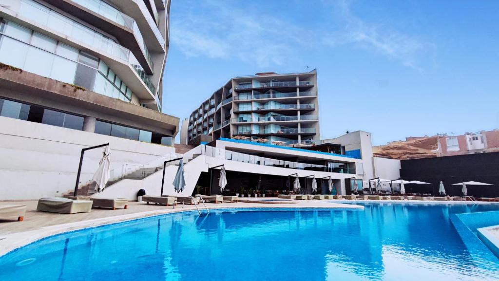 una gran piscina con sillas y un edificio en Apartamento de 3 dormitorios - San Bartolo, en Lima