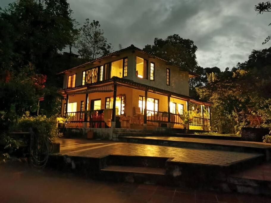 une grande maison éclairée la nuit dans l'établissement Alejandría, reserva natural y las 7 cascadas, à La Vega