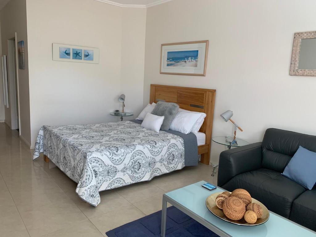 a bedroom with a bed and a couch and a table at Pelicans Rest Shellharbour in Shellharbour