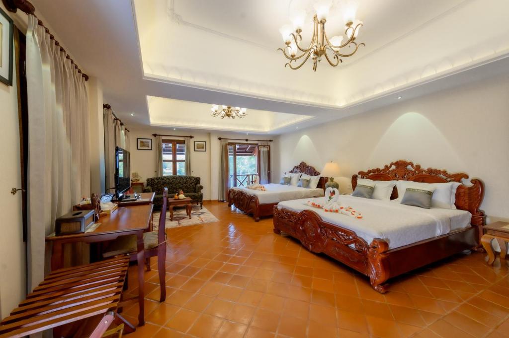 a large bedroom with two beds and a desk at Villa Deux Rivieres in Luang Prabang