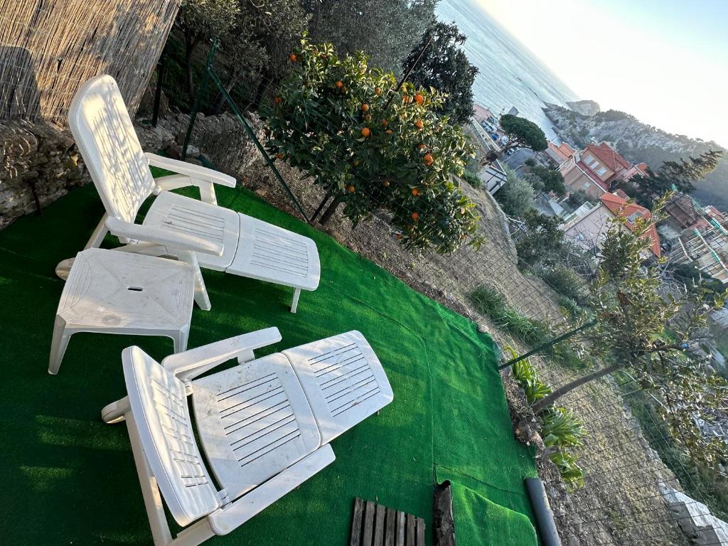 two white chairs sitting on top of a green lawn at Casa del sasso in Bergeggi