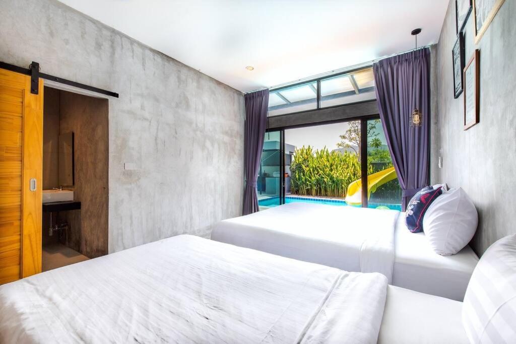Duas camas num quarto com uma janela em EL MAR Pool villa em Ban Bo Fai