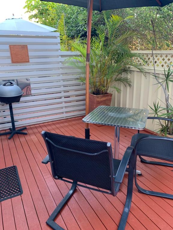 a patio with a table and a chair and an umbrella at Pelicans Rest Shellharbour in Shellharbour