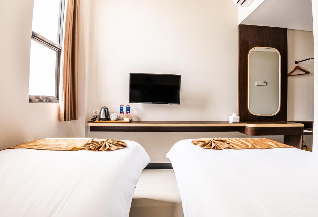 um quarto de hotel com duas camas e uma televisão em KIYANA HOTEL SEMARANG em Jomblang