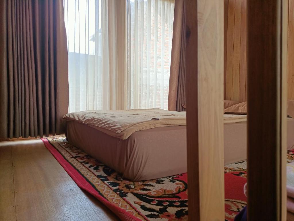 Bett auf einem Teppich in einem Zimmer mit Fenster in der Unterkunft ADK Papandayan Homestay & Tour in Tjisurupan