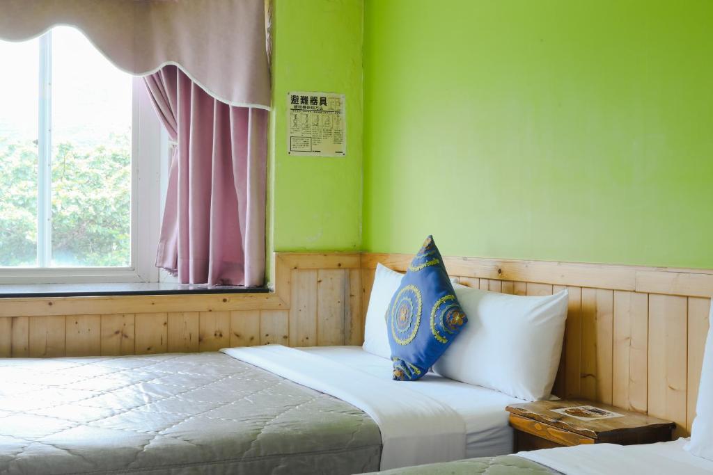 a bedroom with a bed with a window and a pillow at Xing Ji Hotel in Kenting