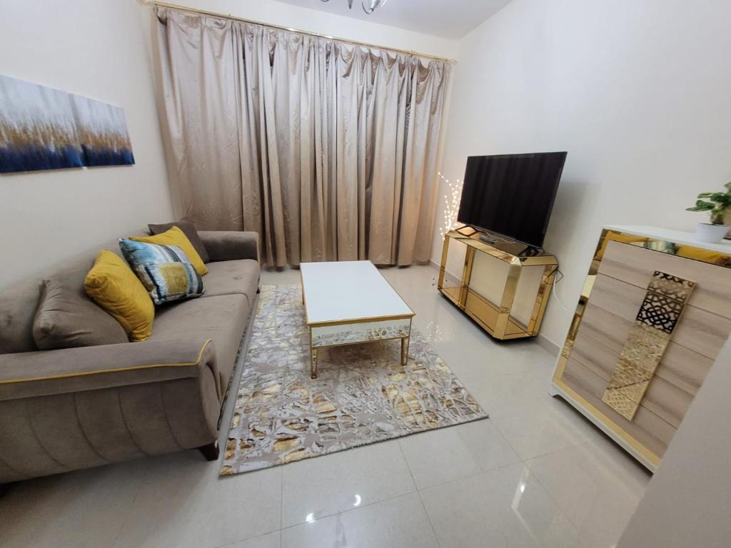 a living room with a couch and a tv at Spacious & Comfortable 1 BR and 1 Living Room Apartment Near Sharjah University City in Sharjah