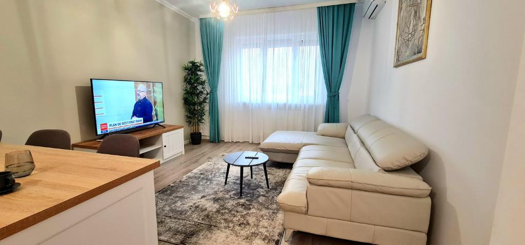 ein Wohnzimmer mit einem Sofa und einem Flachbild-TV in der Unterkunft Apartament momA Oradea in Oradea