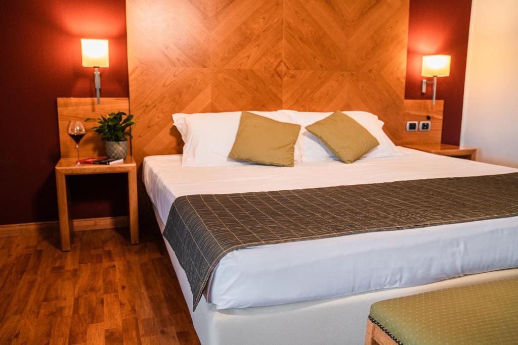 a bedroom with a large bed with a wooden headboard at Hotel Pergola in Legnago
