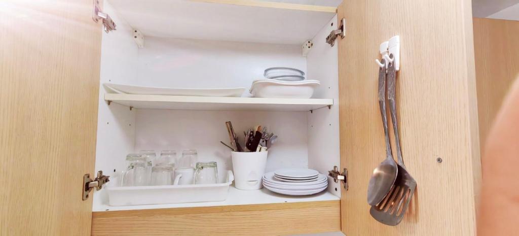 a cupboard with plates and utensils in it at Tagaytay Nordic Nest Staycation at Wind Residences with Netflix Wifi near Sky Ranch in Tagaytay