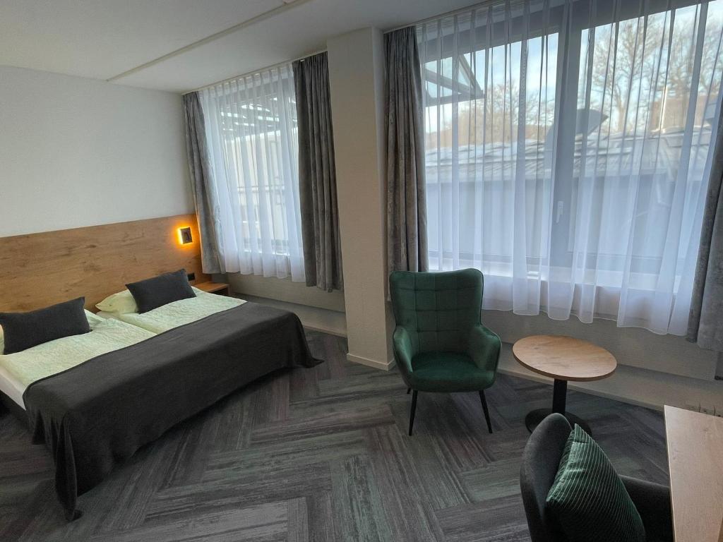 une chambre d'hôtel avec un lit et une chaise dans l'établissement Budget Motel Self Check-In, à Dällikon