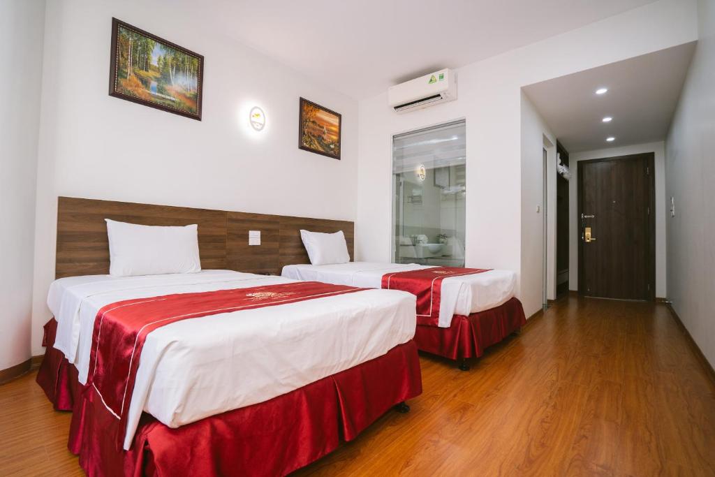 a hotel room with two beds with red sheets at Thành An Hotel in Ha Long