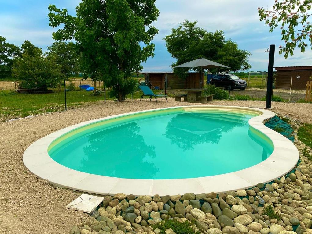une piscine entourée d'un mur de roche. dans l'établissement Au bonheur des animaux, à Auriébat