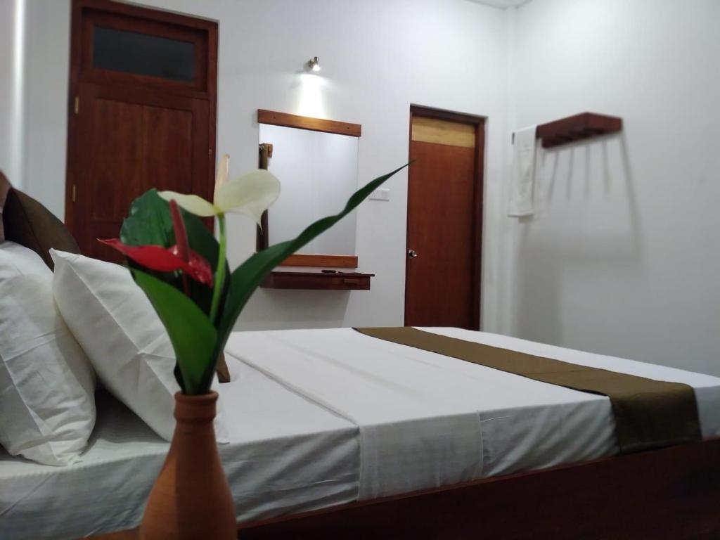 a bedroom with a bed with a vase with a flower at Yala wind in Tissamaharama