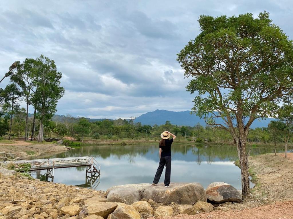 une personne debout sur un rocher devant un lac dans l'établissement Ravin Home ราวินโฮม, à Nakhon Nayok