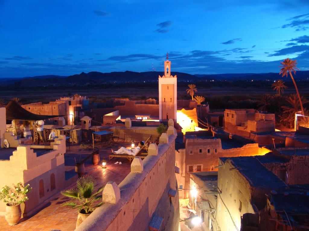 widok na miasto w nocy z wieżą zegarową w obiekcie Dar Kamar w mieście Warzazat