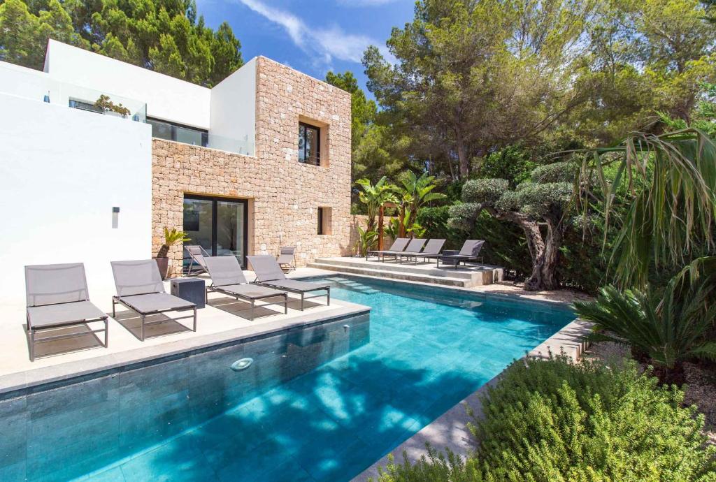 een zwembad met stoelen en een huis bij Villa Higueras in Santa Eularia des Riu
