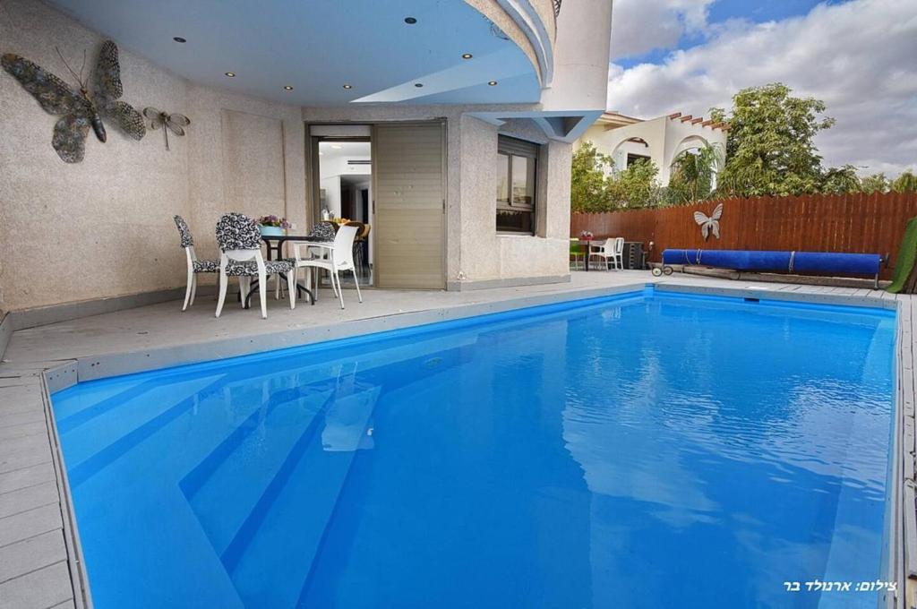 a large blue swimming pool with a table and chairs at לי-ים in Eilat