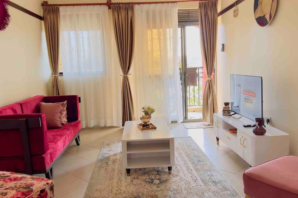 a living room with a red couch and a table at Cozy Apartment within Acacia mall area limits, Unlimited WIFI, Netflix, Free Parking in Kampala