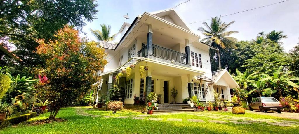 a white house with a yard at ROBUSTA FOREST Home stay in Sultan Bathery