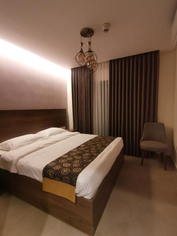 a bedroom with a bed and a chair and a chandelier at Dara apartment hotel in Umm Uthainah