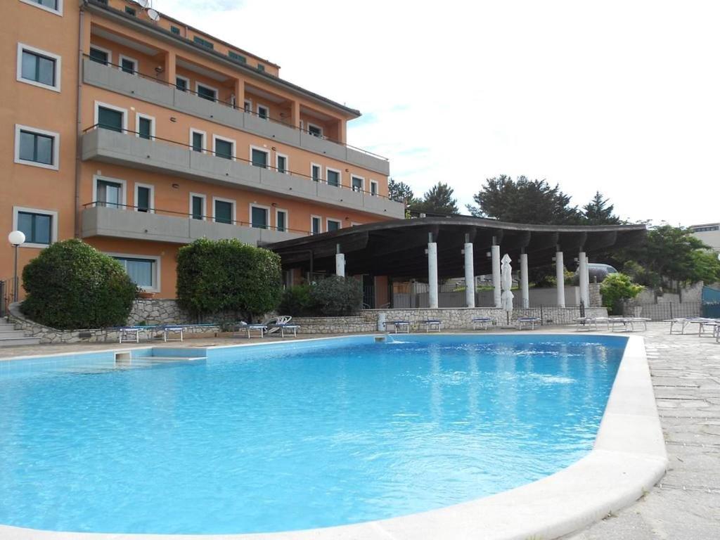 a large blue swimming pool in front of a building at Santangelo Hotel in Monte SantʼAngelo