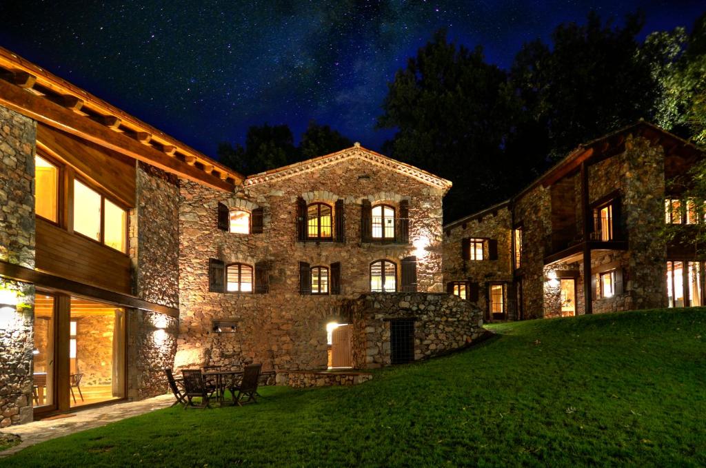 un gran edificio de piedra con luces encendidas por la noche en Masias de Rocabruna, en Rocabruna
