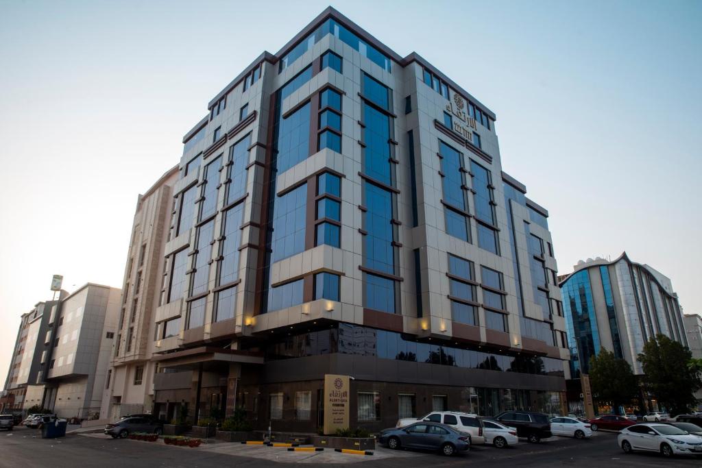 un edificio alto con coches estacionados en un estacionamiento en Al Ertiqaa Hotel, en Yeda