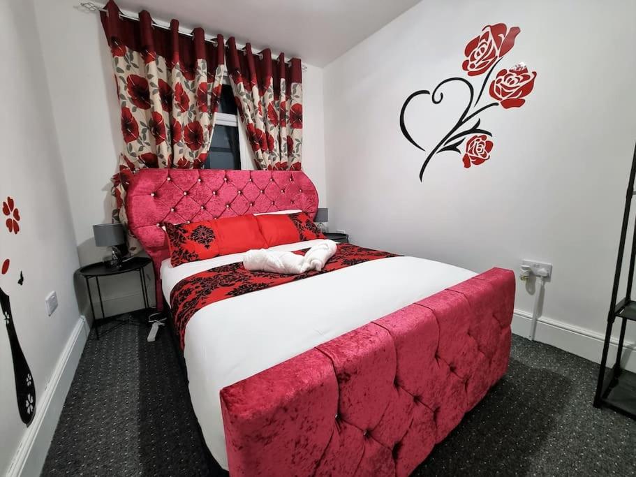 Schlafzimmer mit einem großen Bett mit einem roten Kopfteil in der Unterkunft nc23, setup for your most amazing & relaxed stay + Free Parking + Free Fast WiFi in Farnley