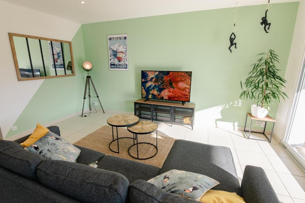 a living room with a couch and a tv at Cozy Nest By the Zoo in Mulhouse