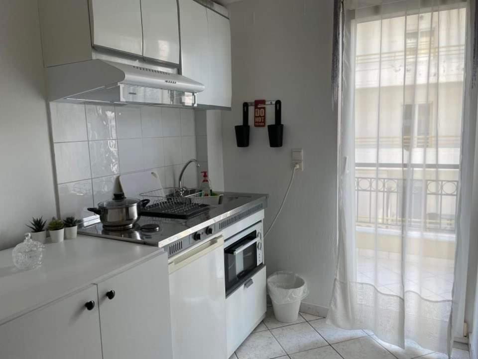 een witte keuken met een fornuis en een raam bij ALEKA KOTSI ROOMS in Igoumenitsa