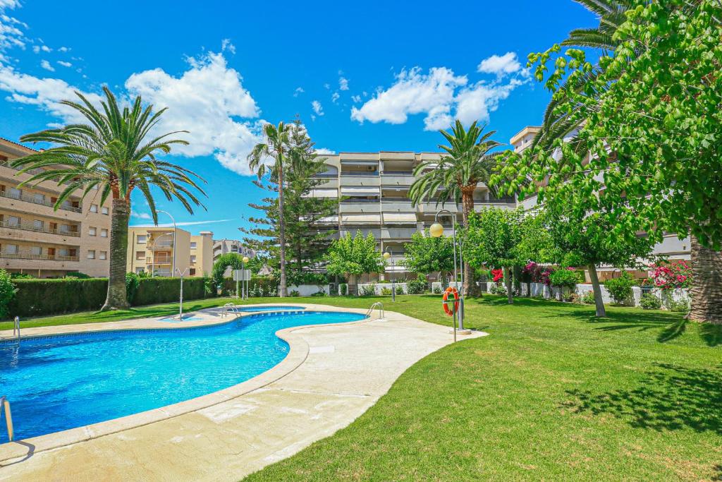 einen Pool in einem Park mit Palmen und einem Gebäude in der Unterkunft Regata Litoral Costa Dorada - ONLY FAMILIES in Cambrils