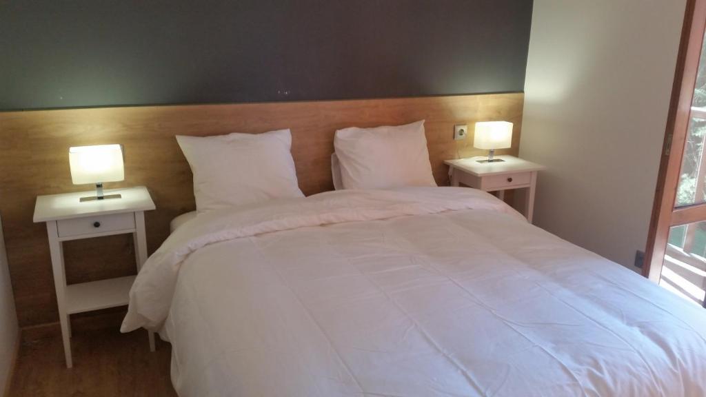1 dormitorio con 1 cama blanca grande y 2 mesitas de noche en Apartamentos Valle de Tena - Biescas en Biescas