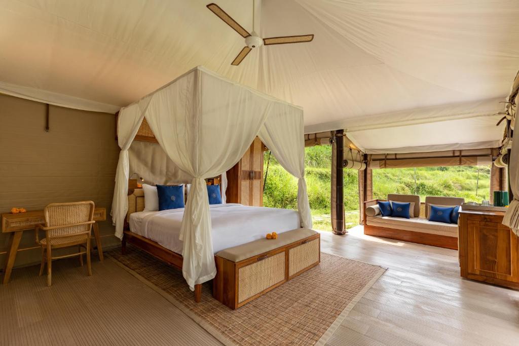 a bedroom with a canopy bed and a desk at Nadi Nature Resort - Adults Only in Tabanan