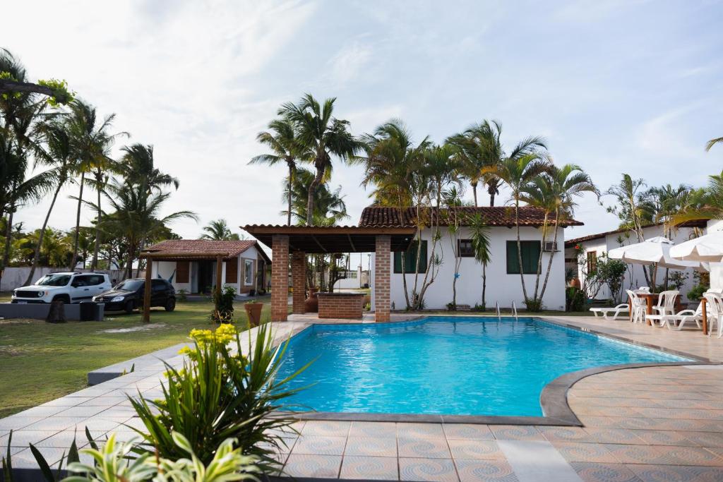 a swimming pool in front of a house with palm trees at Pousada Freitas Alonso in Nova Viçosa