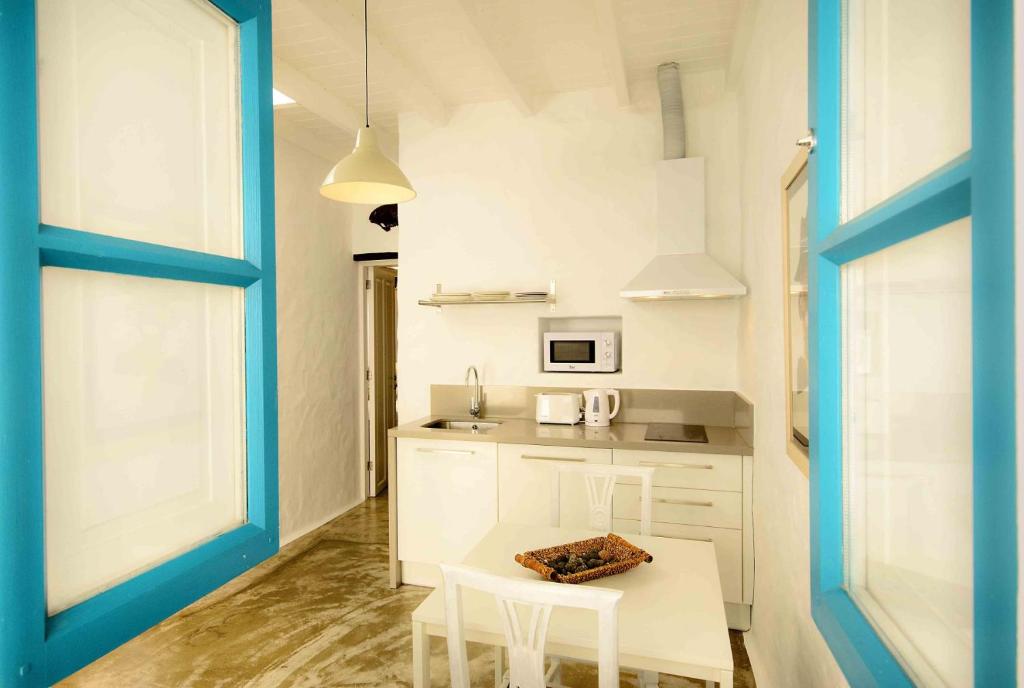 a kitchen with white cabinets and a table and chairs at La Casa de las Salinas in Punta Mujeres