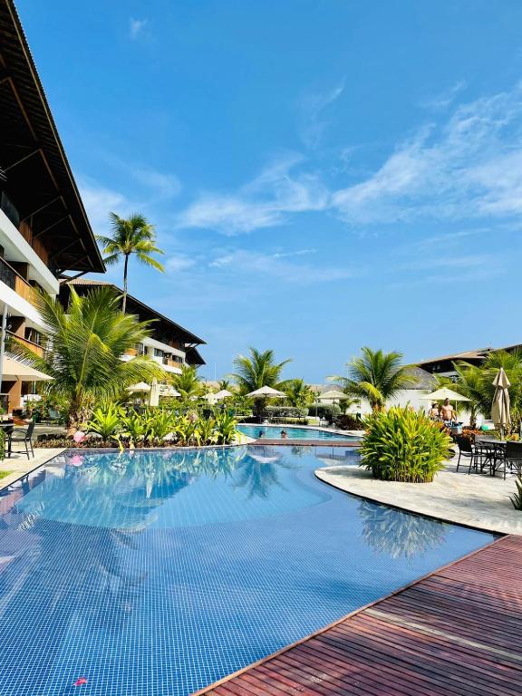 a swimming pool at a resort with palm trees at Flat Resort Beira Mar Porto de Galinhas in Ipojuca