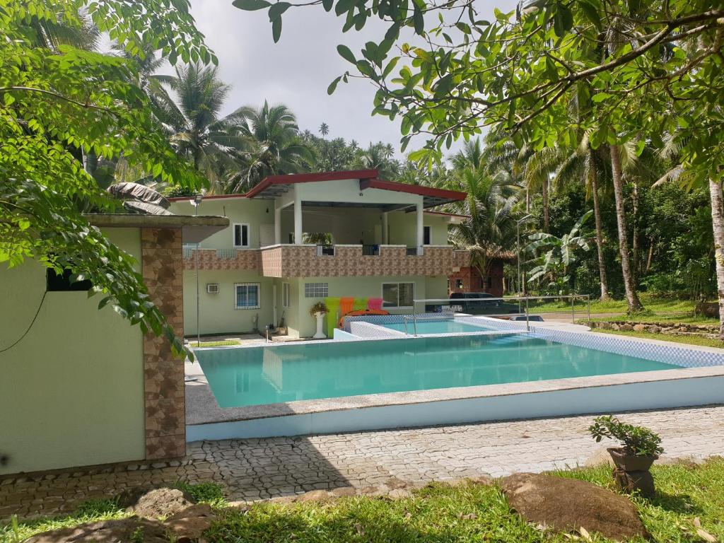 a villa with a swimming pool in front of a house at Pentaqua -Dineros Guest House in Irosin