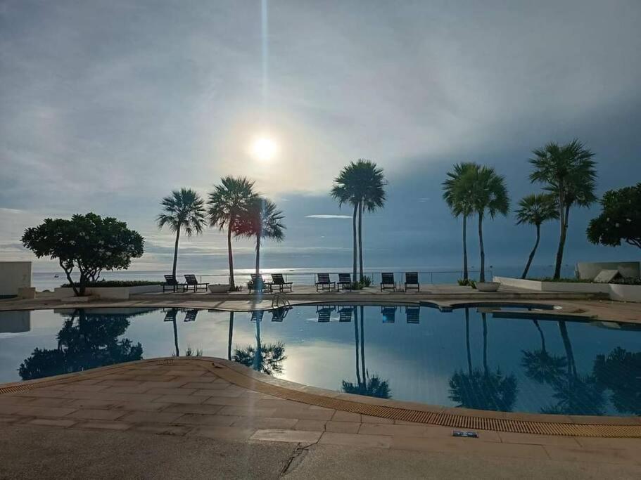 una grande piscina con palme e l'oceano di Seaview Studio with beach access Hua Hin KhaoTao a Ban Bo Kaeo