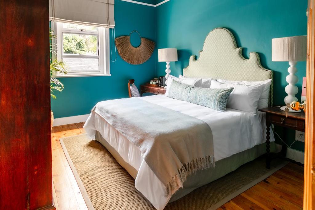 1 dormitorio con 1 cama con paredes azules en The Belmont, en Franschhoek