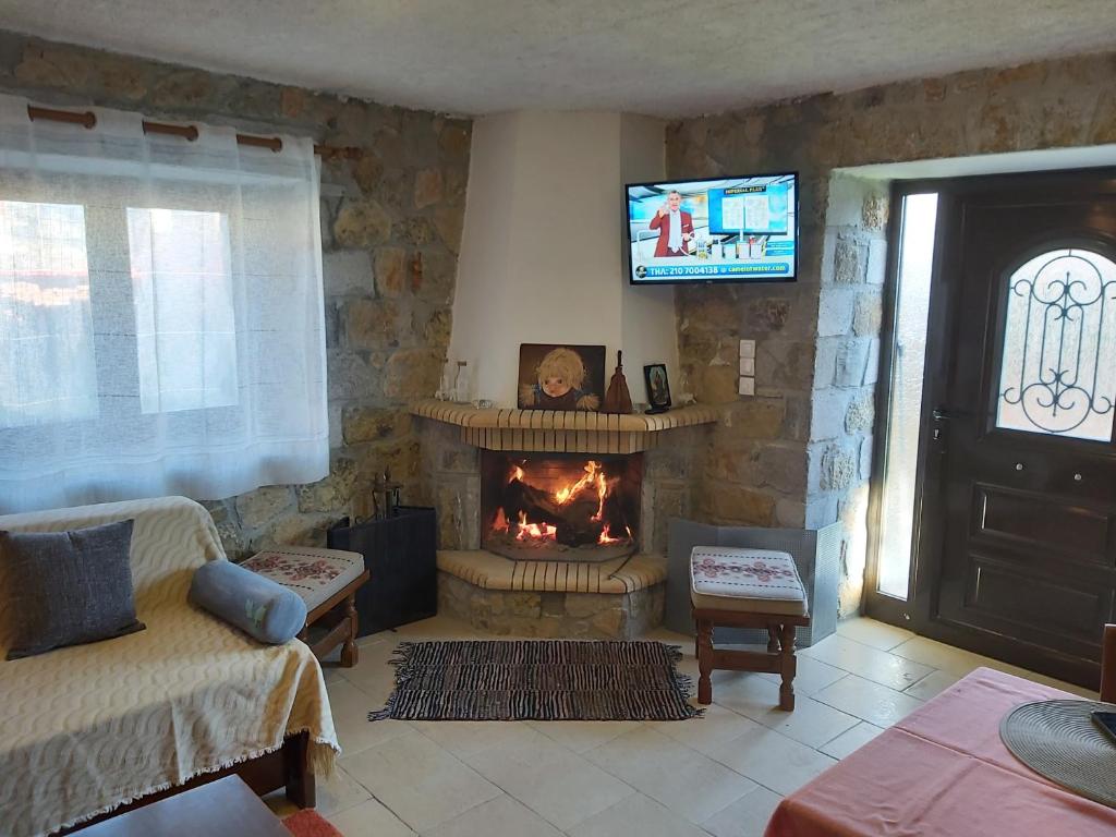 ein Wohnzimmer mit einem Kamin und einem TV in der Unterkunft Stymfalia stone house 