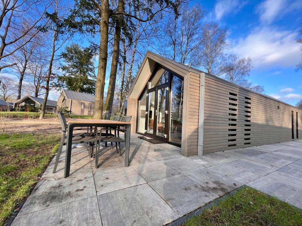 een klein huis met een tafel en stoelen op een patio bij Holiday Home Maridu Forest in Arnhem