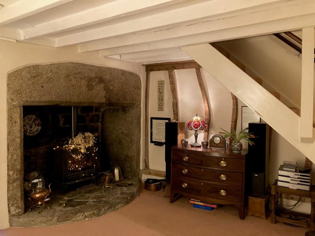 a living room with a fireplace and a dresser at Little Reeds in Bovey Tracey