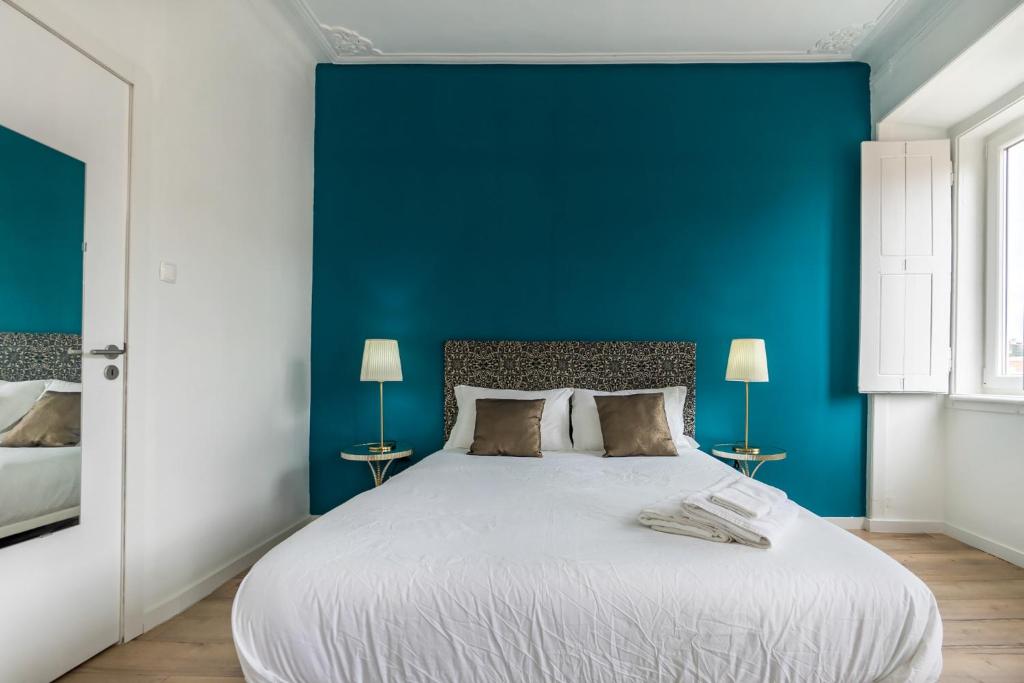 um quarto com uma cama grande e uma parede azul em The Color Hostel em Lisboa