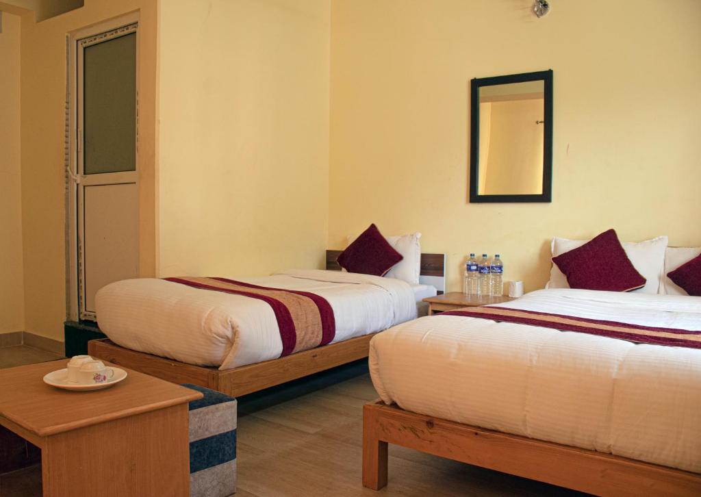 Habitación de hotel con 2 camas y espejo en HOTEL LUMA INN, en Pokhara