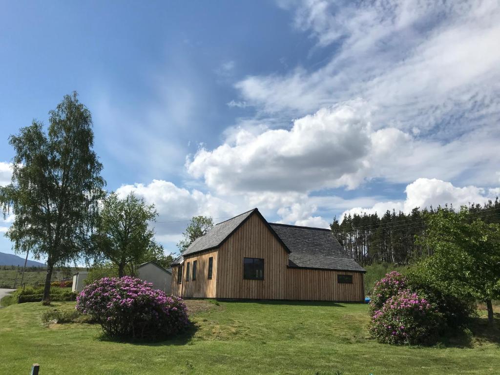 a barn in a field with flowers in front of it at Old Schoolhouse in Lairg