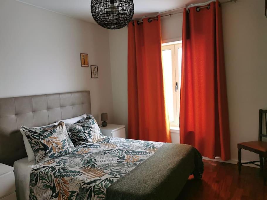 ラーヴラにあるDunas Flatのベッドルーム1室(赤いカーテンと窓付きのベッド1台付)